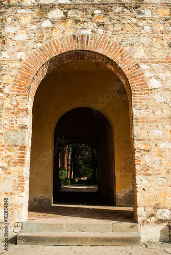 Passaggio ad arco di mattoni, muro di pietre antico © Andreaphoto