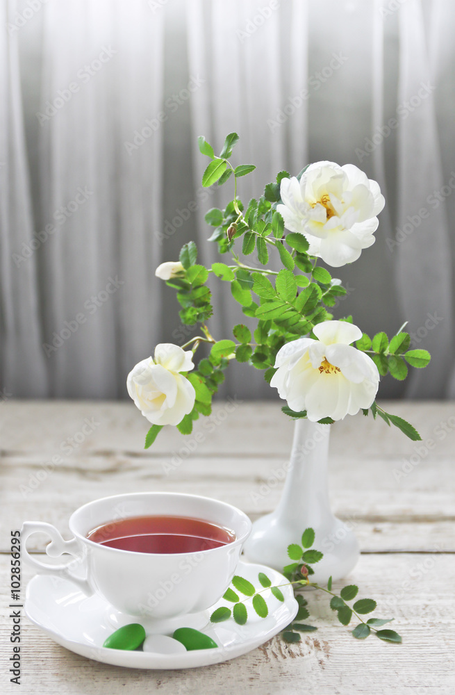 cup of tea and roses in a vase cup of tea and roses in a vase