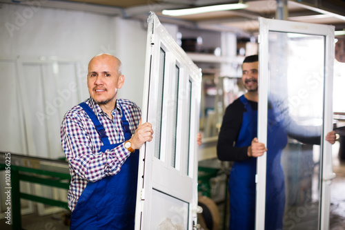 Workers with PVC windows and doors .