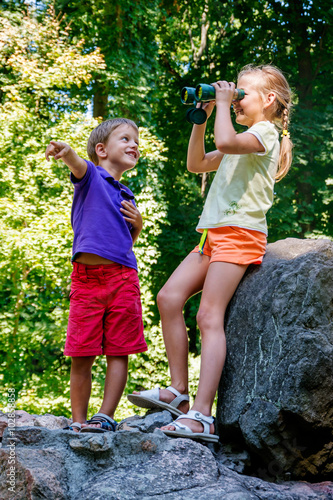 Children playing outdoors and having fun together with binoculars