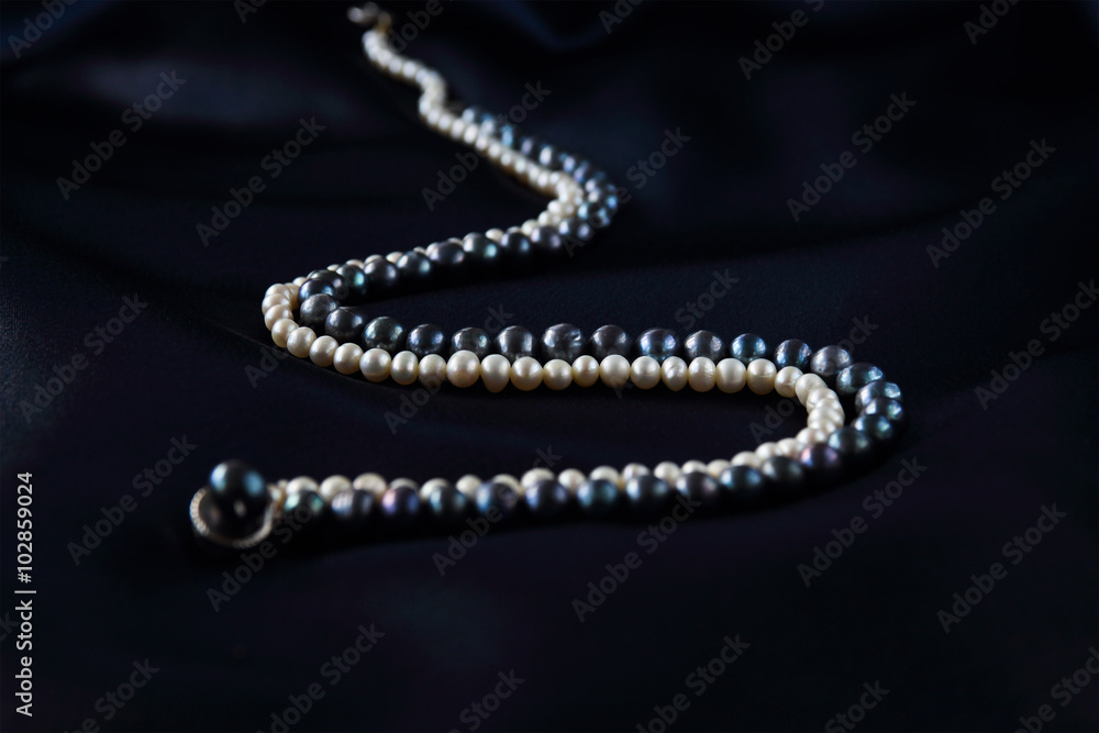 a necklace of black and white pearls on a dark blue background a necklace of black and white pearls on a dark blue background