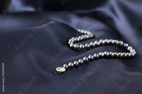 a necklace of black pearls on a dark blue background