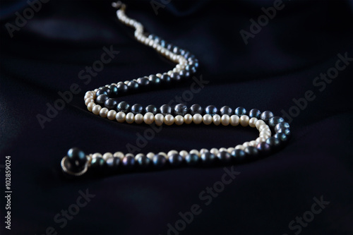 a necklace of black and white pearls on a dark blue background
