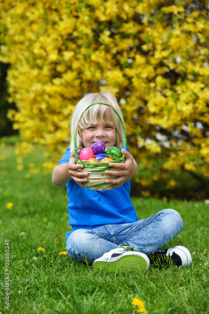Smiling little boy holding basket full of colorful easter eggs Smiling little boy holding basket full of colorful easter eggs