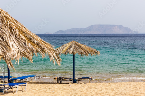 Blue sea, golden sand, sunbeds and umbrellas on the beach. Ios i