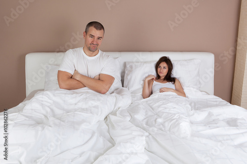Young couple lying in bed and woman is very small but self-confi