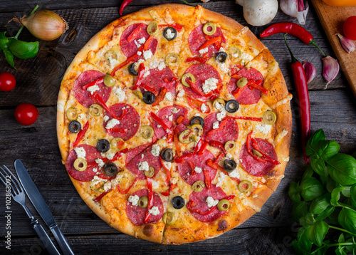 Freshly baked pizza with feta cheese, olives, salami and paprika
