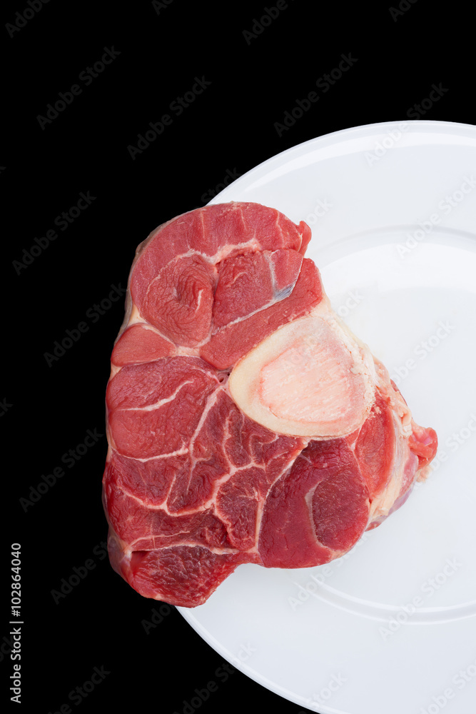 one piece of raw beef meat with the bone in the middle on black background one piece of raw beef meat with the bone in the middle on black background