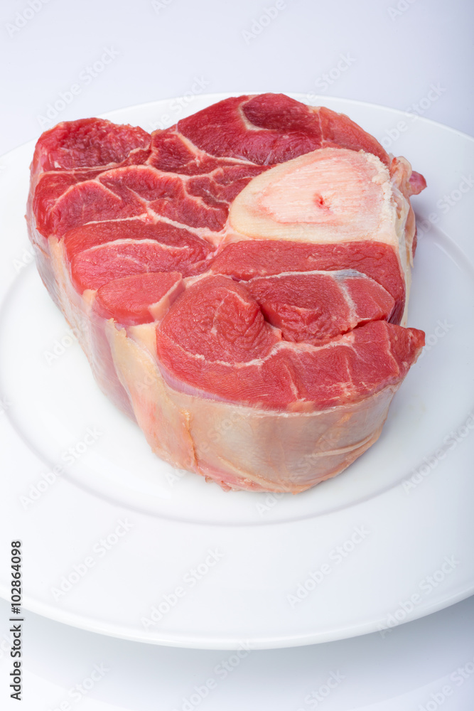 one piece of raw beef meat with the bone in the middle on a white background one piece of raw beef meat with the bone in the middle on a white background