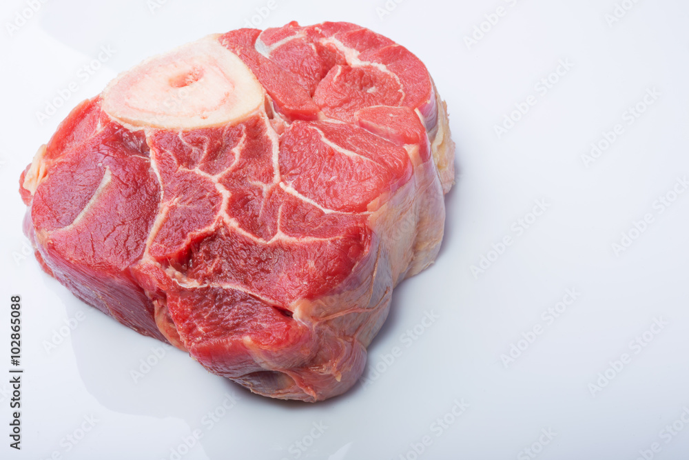 one piece of raw beef meat with the bone in the middle on a white background one piece of raw beef meat with the bone in the middle on a white background