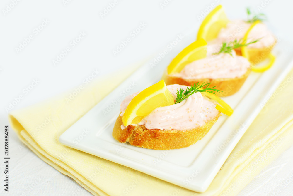 Taramasalata canapé, fish-roe spread bites with lemon slices over bread Taramasalata canapé, fish-roe spread bites with lemon slices over bread