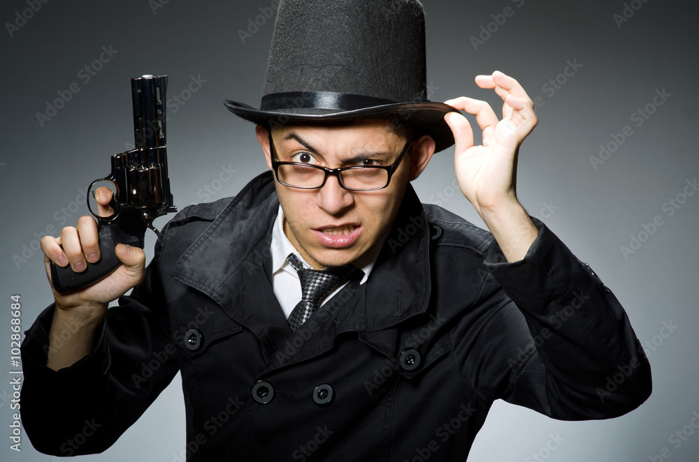 Criminal in black coat holding hadgun against gray Criminal in black coat holding hadgun against gray