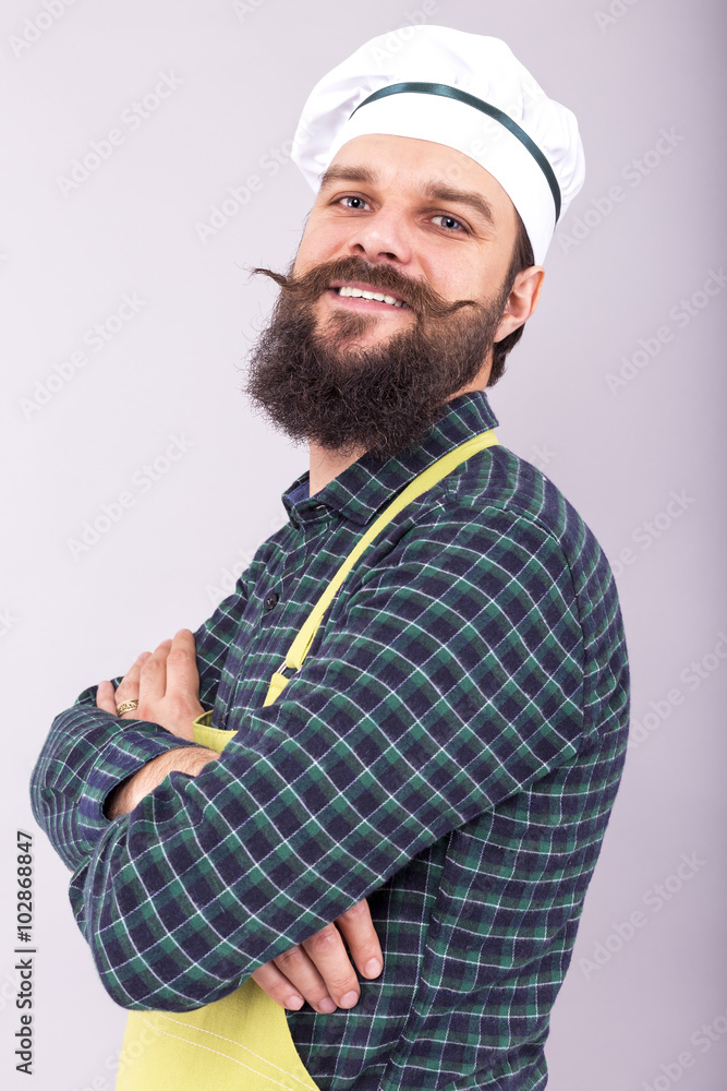 Studio shot of a bearded man with cook hat  holding arms crossed