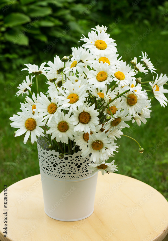  букет полевых цветов ромашек на фоне круглого стола в саду