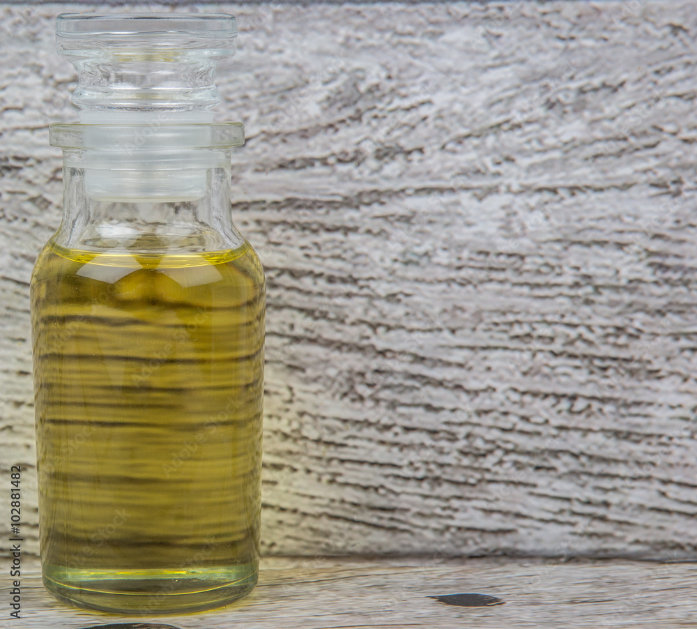 Sesame seed oil in glass vial over wooden background Sesame seed oil in glass vial over wooden background