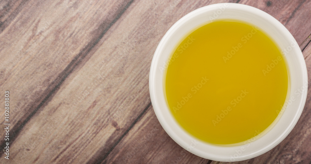 Avocado oil in white bowl over wooden background Avocado oil in white bowl over wooden background