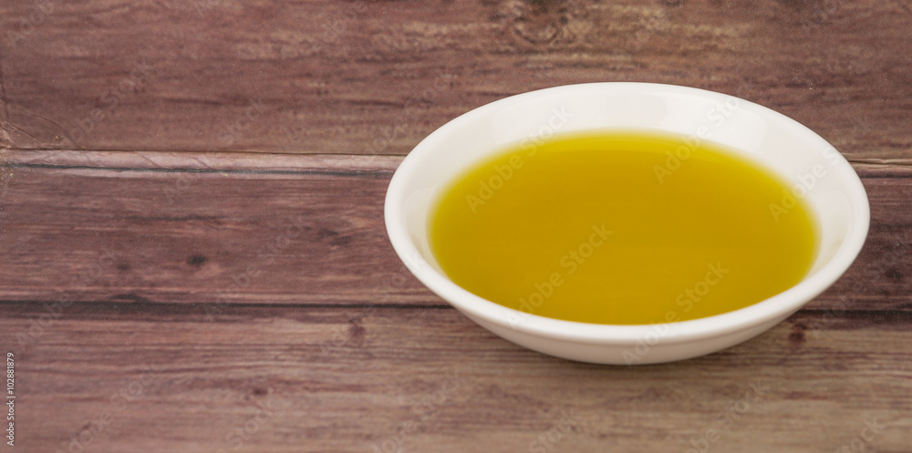 Avocado oil in white bowl over wooden background Avocado oil in white bowl over wooden background