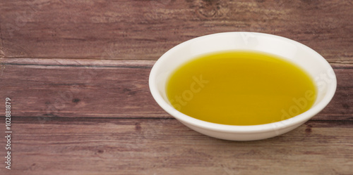 Avocado oil in white bowl over wooden background