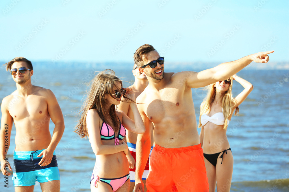 Happy couple and their playful friends relaxing at the beach, outdoors Happy couple and their playful friends relaxing at the beach, outdoors