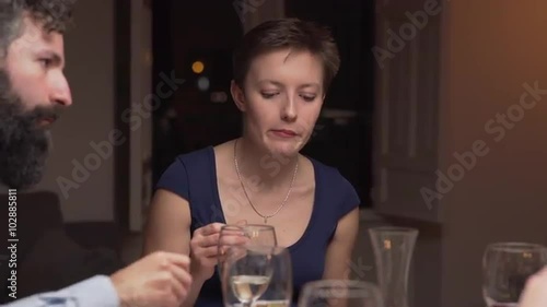 Young woman in a dinner with some friends. She is eating and listening. The camera moves to the left. 4K, UHD