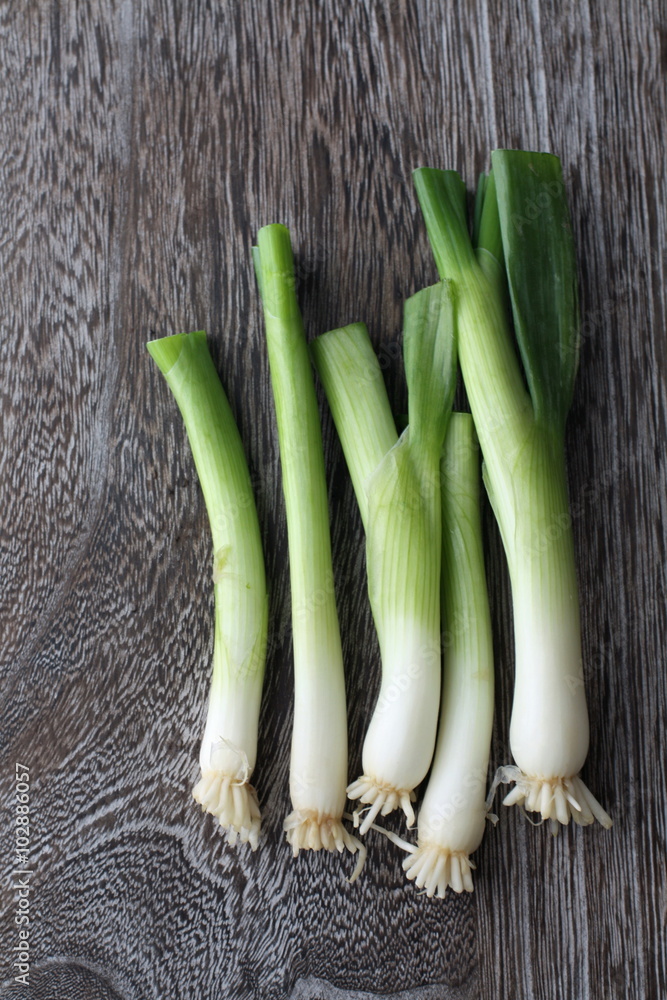 Green onions with roots on a wooden background Green onions with roots on a wooden background