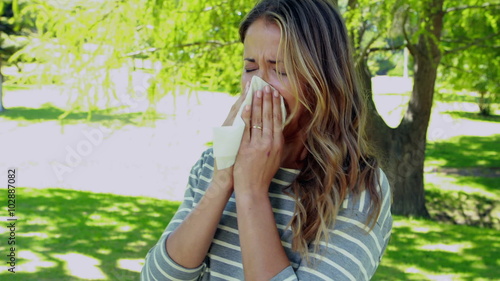 Woman blowing nose with tissue paper photo