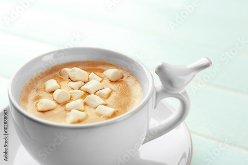 Cup of hot cacao with marshmallow on blue table