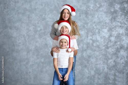 Boys and girl in Santa hats on grey background