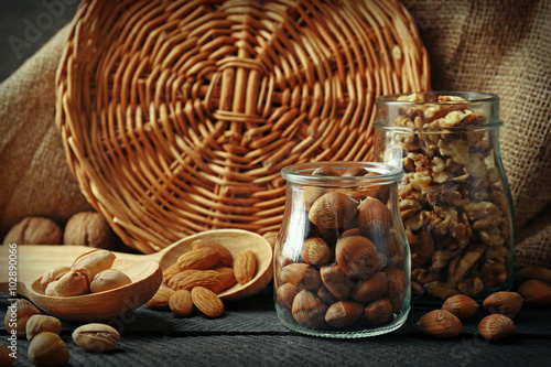 Mix of nuts in the glass jars and wooden spoon, on the table