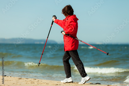 Nordic walking. Woman hiking on the beach.
