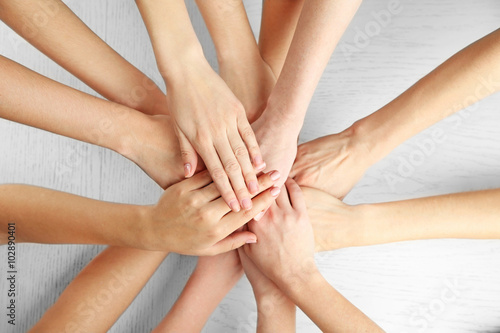 Group of people putting their hands together on wooden background