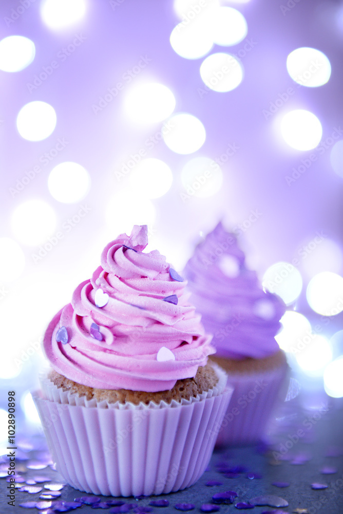 Two cupcakes on a glitter background, close up