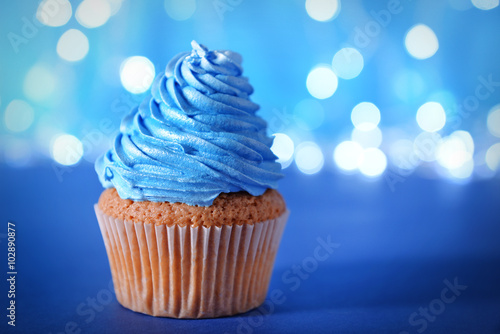 Cupcake with blue cream icing on a glitter background, close up