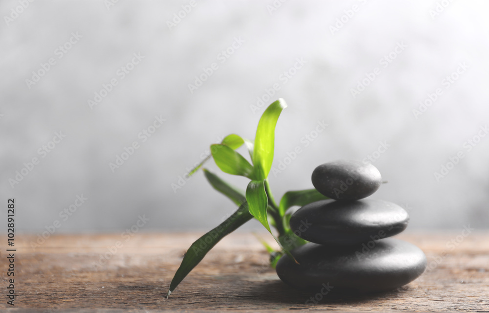 Spa stones with bamboo on wooden table against grey background Spa stones with bamboo on wooden table against grey background
