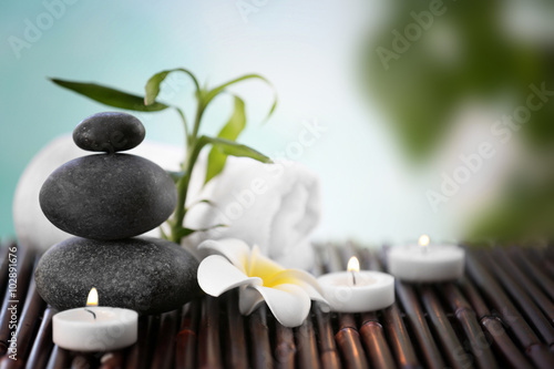 Spa stones with towel  candles and tropical flower on blurred background