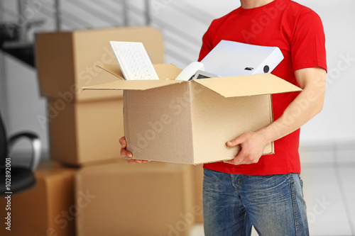 Man holding carton box full of office stationery in the room, close up © Africa Studio