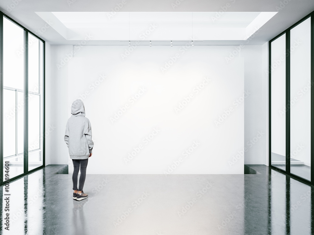 Young woman in empty modern gallery looking at the blank canvas. Young woman in empty modern gallery looking at the blank canvas.