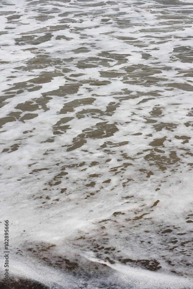 Obraz premium Frothy waves on beach - Frothy and foamy sea waves on a tropical beach.