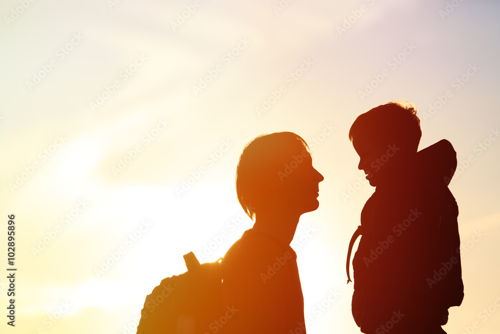 father and little son with backpacks travel at sunset