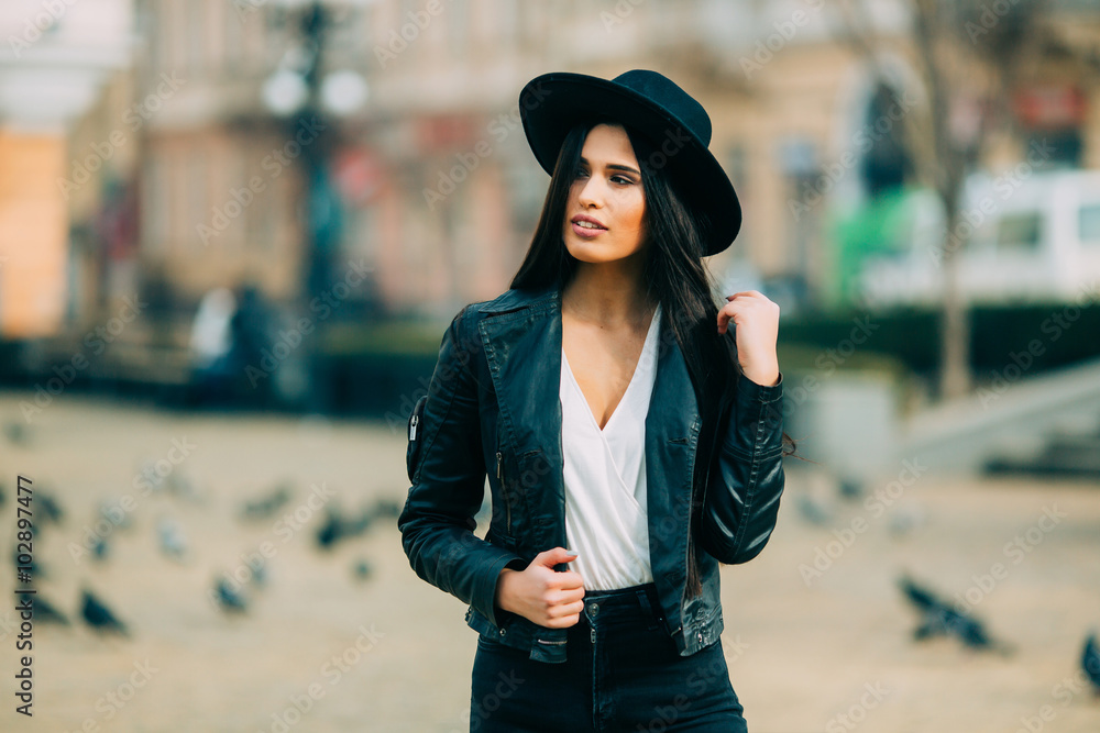 Portrait of young beautiful casual girl in jacket an black hat walking on spring city street. Spring outfit, Spring street look. Portrait of young beautiful casual girl in jacket an black hat walking on spring city street. Spring outfit, Spring street look.