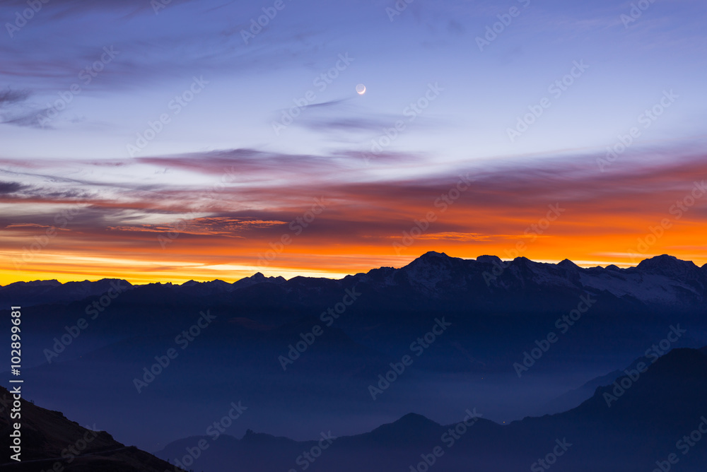 Mountain silhouette and stunning sky with moon at sunset