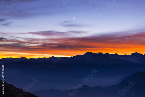 Mountain silhouette and stunning sky with moon at sunset