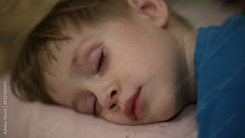 Little boy falls asleep, his eyelids heavy and eyes closed
Little boy falls asleep, his eyelids heavy and eyes closed