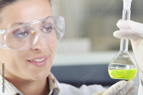 Attractive young PhD student scientist observing the green indicator color shift after the solution destillation in chemical laboratory
