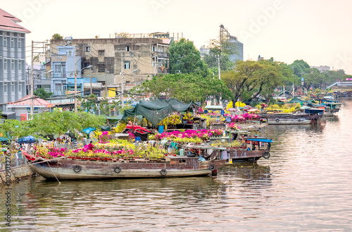 Ho Chi Minh City, Vietnam - February 6th, 2016: Flowers along river boat bustle day festival with buyers, sellers busy river also traditional annual meeting market in Ho Chi Minh City, Vietnam photo