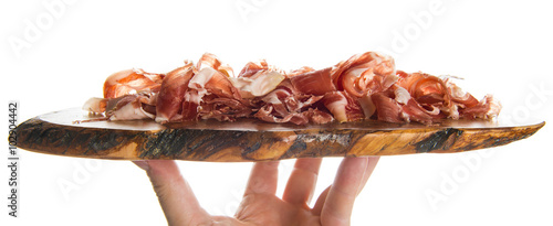 Fotografija Tabla de olivo con jamón serrano cortado a cuchillo en virutas aislado sobre fon