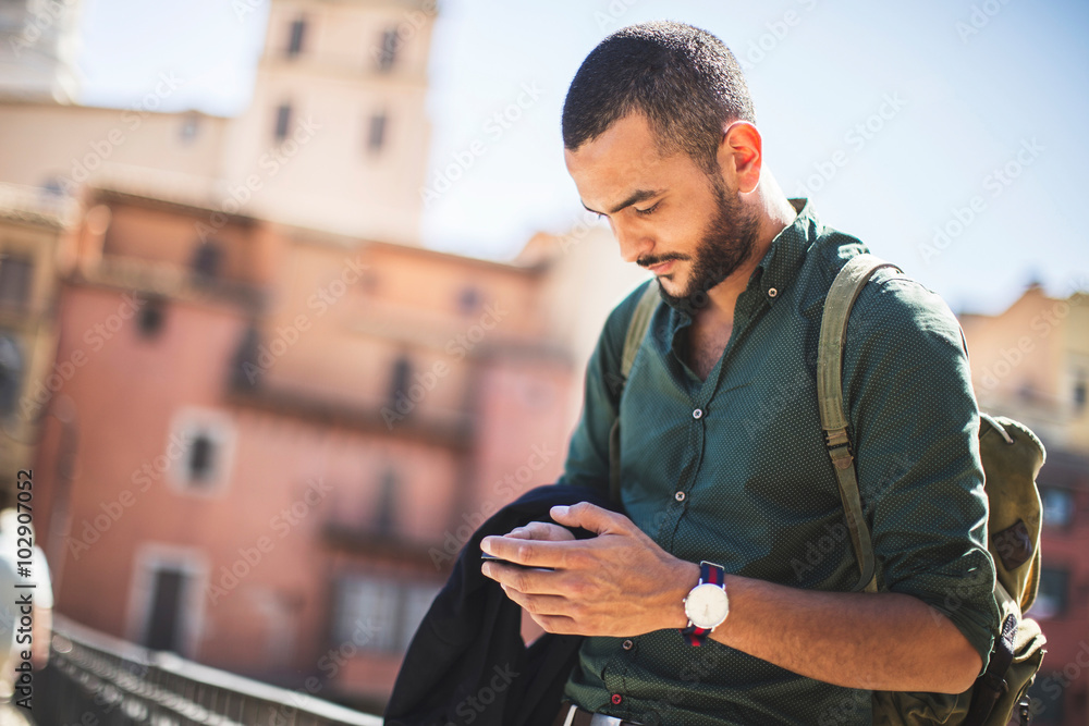 Young bearded traveller using his smartphone