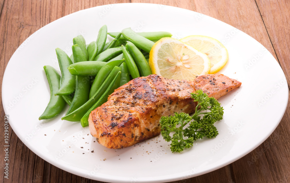 Grilled salmon with lemon, green bean and herb, on white dish. Dinner concept Grilled salmon with lemon, green bean and herb, on white dish. Dinner concept