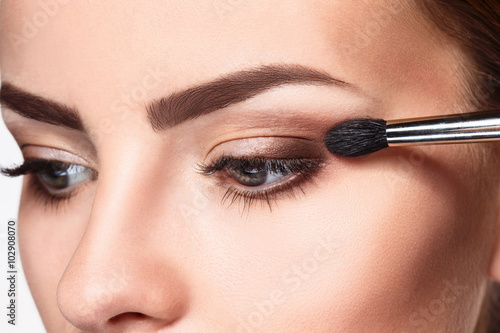 Fotografie Beautiful female eyes with bright blue make-up and brush