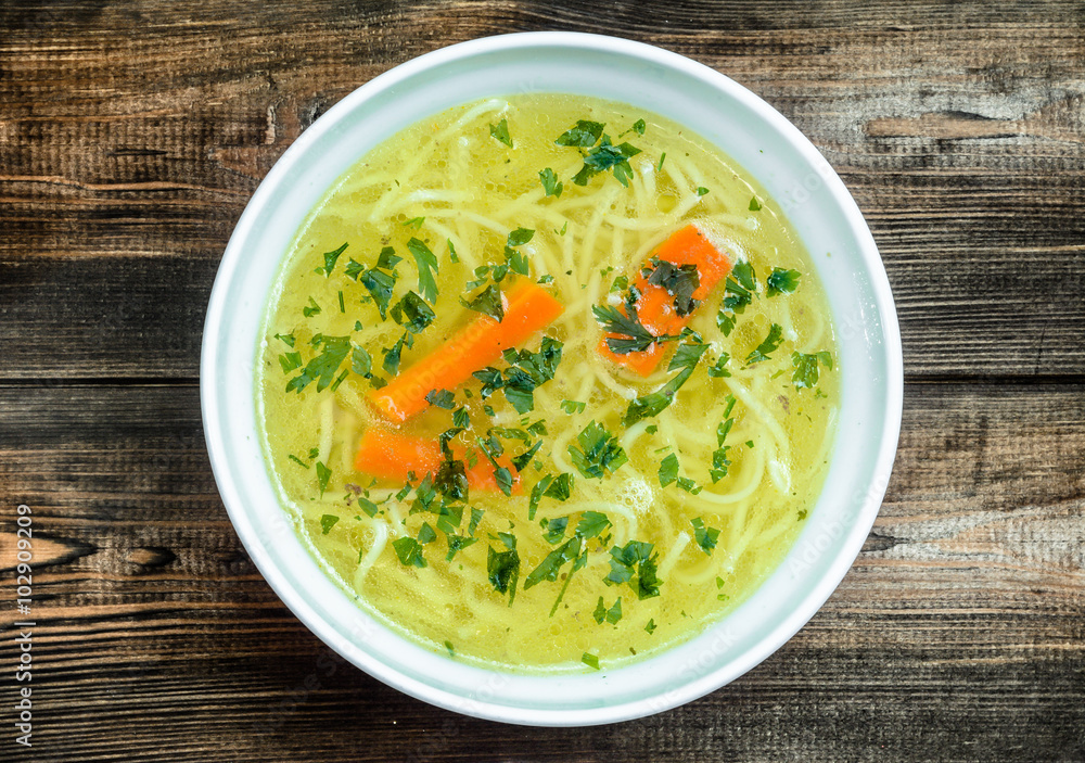 Chicken broth soup with noodles on a wooden table. Chicken broth soup with noodles on a wooden table.